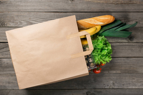 Different food in paper bag on wooden table - Φωτογραφία, εικόνα
