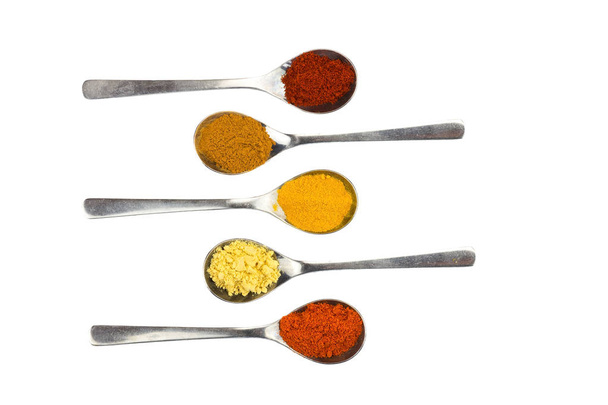 Various seasoning spices on metal spoons - Фото, изображение