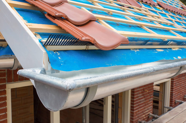 Ψευδάργυρος υδρορροή και κεραμίδια στον αγωνιστικό χώρο της οροφής του σπιτιού - Φωτογραφία, εικόνα