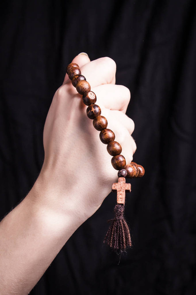 Ροζάριο και σταυρό στα γυναικεία χέρια σε σκούρο φόντο  - Φωτογραφία, εικόνα