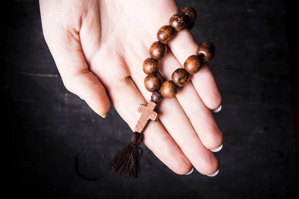 Rosary and cross in female hands on a dark background  - Foto, Bild