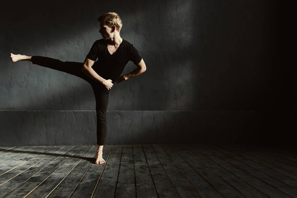 Trained young man dancing in the dark lighted room - 写真・画像