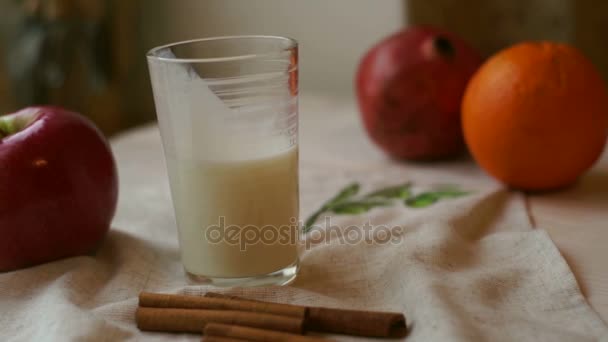 Bicchiere di latte con mela rossa e arancia sulla tovaglia. Cibo colazione
 - Filmati, video