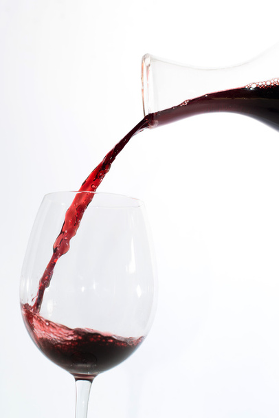 rode wijn die in een glas giet - Foto, afbeelding