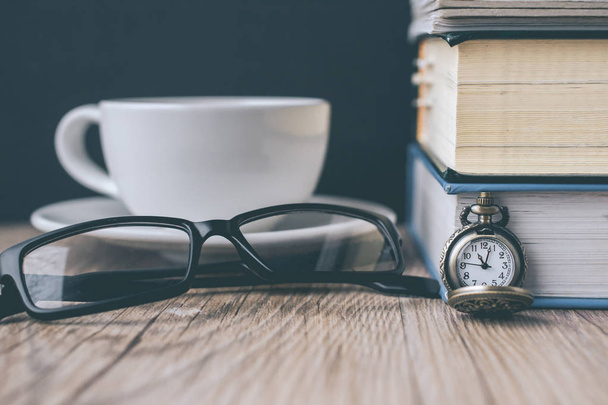 Relógio de bolso e xícara de café com livro e os óculos em madeira
 - Foto, Imagem