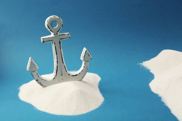 Old anchor in sand on blue background. Columbus Day concept - Fotografie, Obrázek