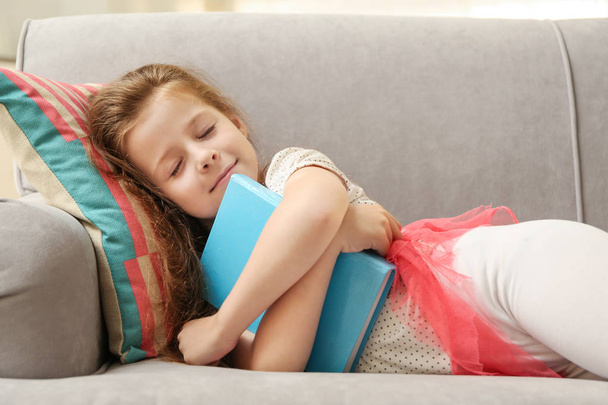 Cute girl with book on couch - Фото, изображение