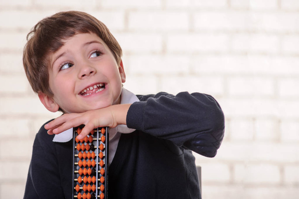 Portret van basisschool jongen met behulp van abacus geestelijke rekenkundig. - Foto, afbeelding