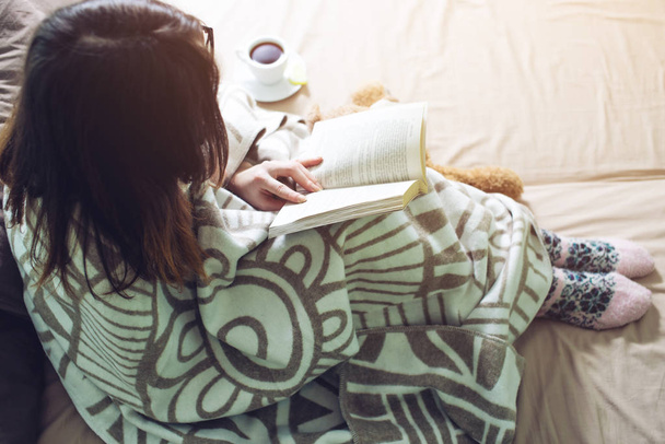 Женщина, завернутая в книгу для чтения под теплым одеялом
 - Фото, изображение