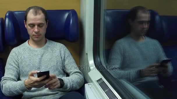 Ευτυχισμένος άνθρωπος λαμβάνει την έδρα του σε ένα τρένο και την αποστολή μηνυμάτων στο κινητό του τηλέφωνο. Σύγχρονη ασύρματων τεχνολογιών επικοινωνίας. βίντεο 4k - Πλάνα, βίντεο