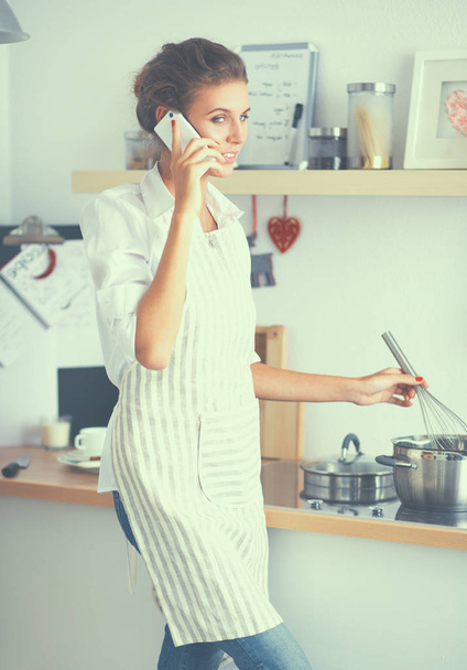 Portrait a smiling woman with phone in kitchen at home - 写真・画像