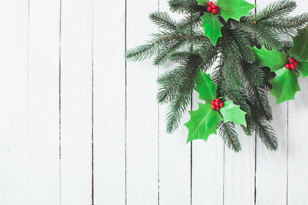 Holly and fir twigs on wood wall - Foto, imagen