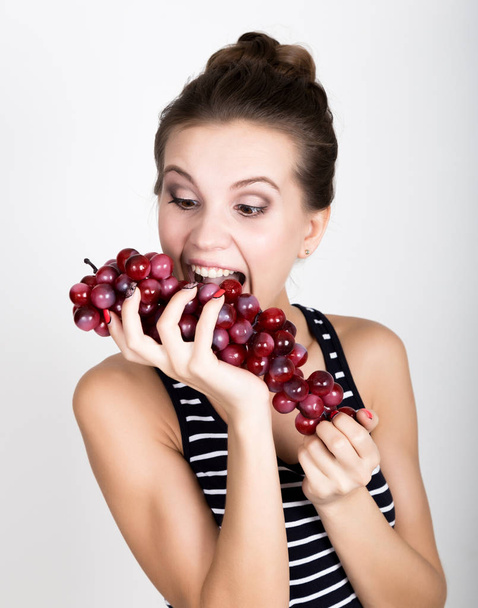 Young smiling woman holding fresh red bunch of grapes. - Фото, зображення
