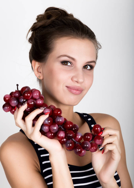 Young smiling woman holding fresh red bunch of grapes. - Fotoğraf, Görsel