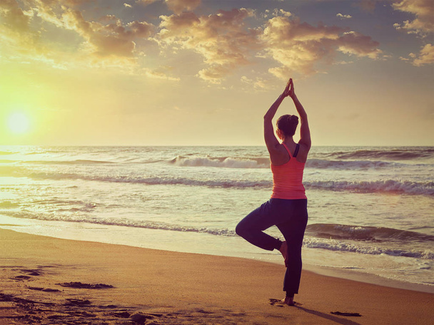 Joven mujer en forma deportiva haciendo yoga asana árbol en la playa
 - Foto, imagen