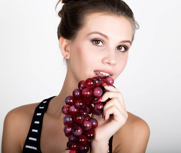 Young smiling woman holding fresh red bunch of grapes. - Foto, imagen