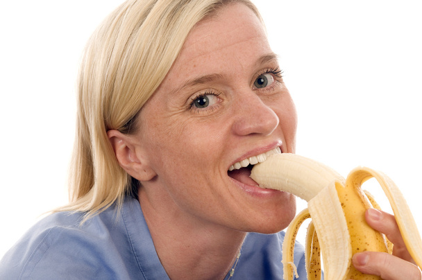 Enfermera o médico mujer médica comiendo una fruta fresca saludable
 - Foto, Imagen