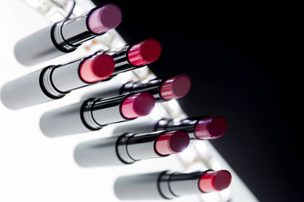 Instellen van matte Lipstick in rood en natuurlijke kleuren op witte zwarte achtergrond. Mode kleurrijke lippenstiften. Professionele make-up schoonheid. Knipperende bokeh . - Foto, afbeelding