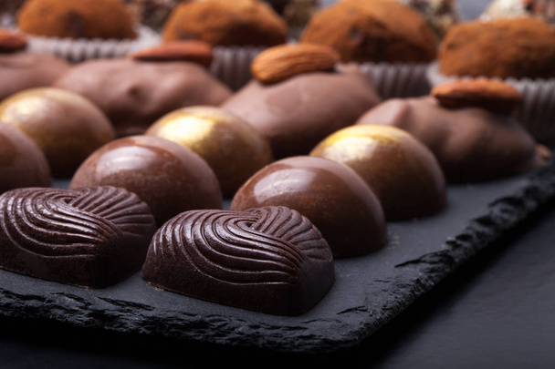 Different kinds of chocolate candies on a slate background - Foto, Imagen