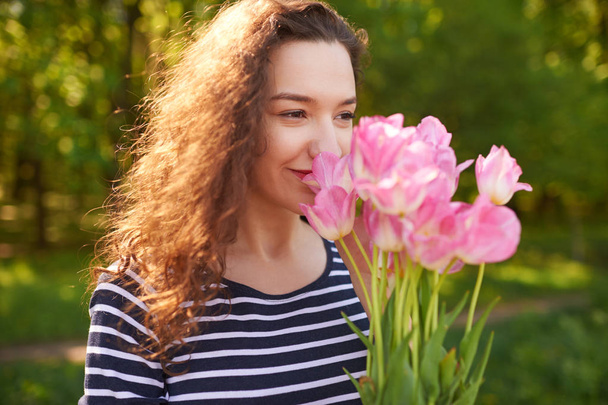 Young cute woman smelling pink flowers - Fotografie, Obrázek