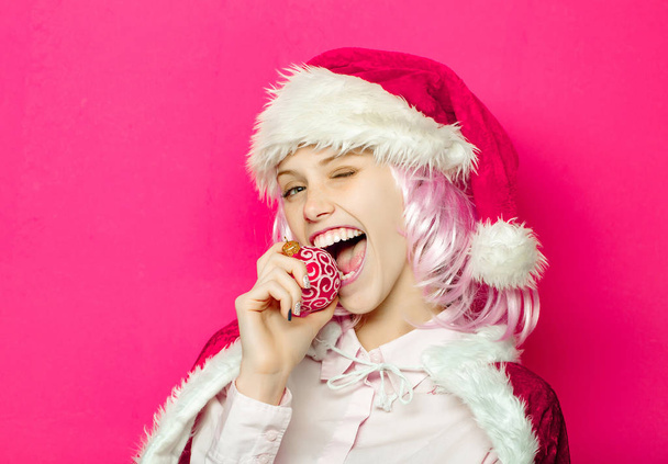 Winking girl bites Christmas bauble - Fotó, kép