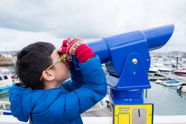 Joven asiático chico buscando en telescopio en puerto
 - Foto, Imagen