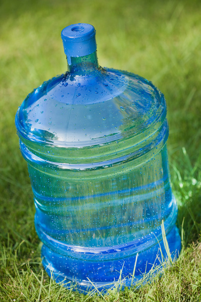 Большая бутылка воды на зеленом фоне травы
 - Фото, изображение