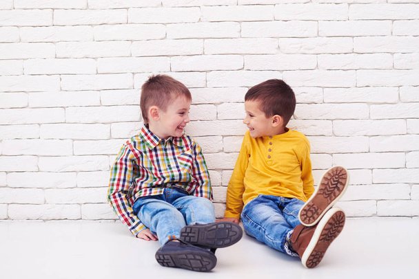 Happy two little boys sitting on floor and smiling at each other - Fotó, kép