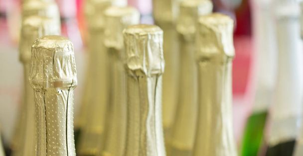 Шампанські золоті пляшки шиї і верхні шапки стоять на світлому фоні в наявності
. - Фото, зображення