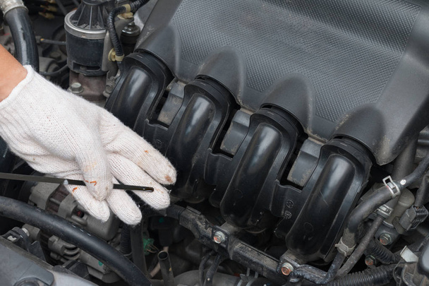Personas, técnico comprobar el nivel de aceite del motor del coche antes de cambio o mantenimiento, palo de aceite en el coche
 - Foto, imagen
