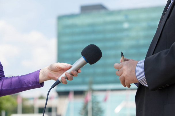 Female journalist interviewing businessman, corporate building in background - Foto, Bild
