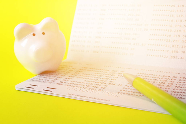 Savings account passbook, piggy bank and pen on yellow background - Photo, Image