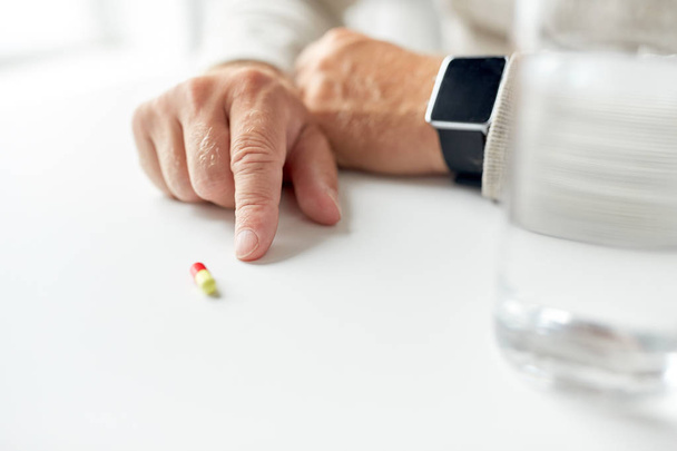 close up of old man hand with pill and smart watch - Foto, imagen