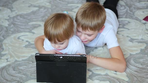 lapset näyttävät sarjakuvia tabletin pc lattialla
 - Materiaali, video