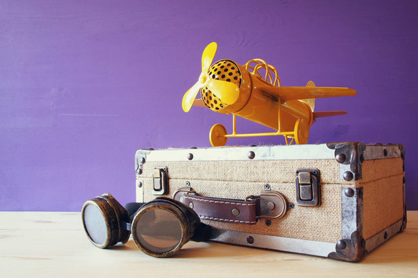 vintage toy plane and old suitcase next to pilot glasses - Photo, image