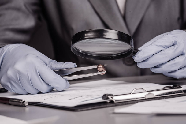Detective through a magnifying glass looking at a evidence - Foto, Imagen