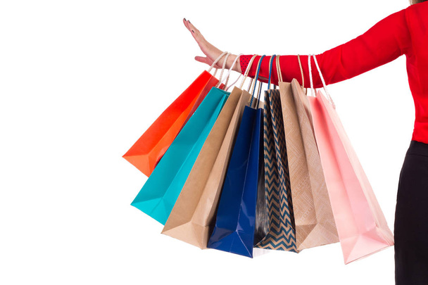 Paquetes de compras coloridos y brillantes colgados en el brazo de manga roja femenina
 - Foto, Imagen