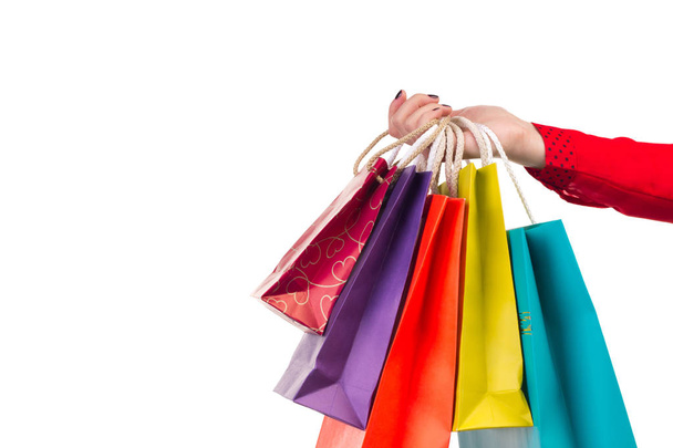 Paquets shopping polyvalents et lumineux suspendus au bras féminin à manches rouges
 - Photo, image