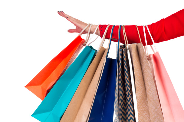 Multicolored and bright shopping packages hanging on female red-sleeaved arm - Photo, Image