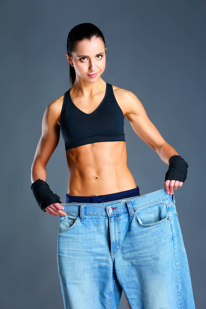 Young fitness woman showing that her old jeans - Photo, Image
