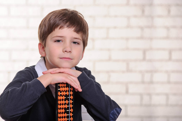 Portret van basisschool jongen met behulp van abacus geestelijke rekenkundig. - Foto, afbeelding