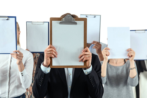 Team of businesspeople holding a folders near face isolated on white background - Foto, imagen