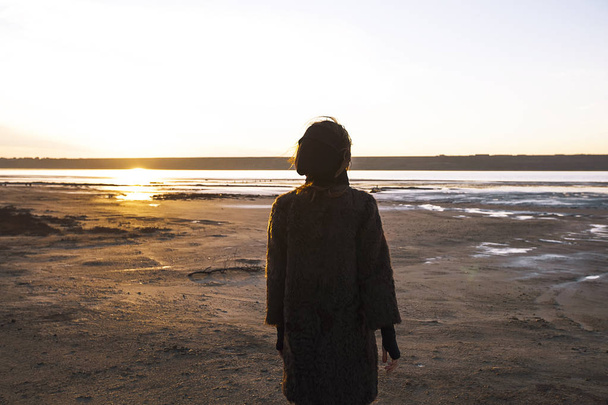 Girl in a coat walks on the lake - 写真・画像