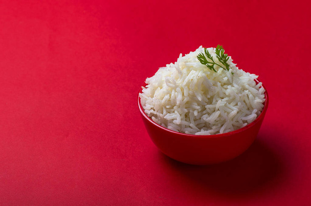 Vařené obyčejný bílá basmati rýže v červené misky na červeném pozadí - Fotografie, Obrázek