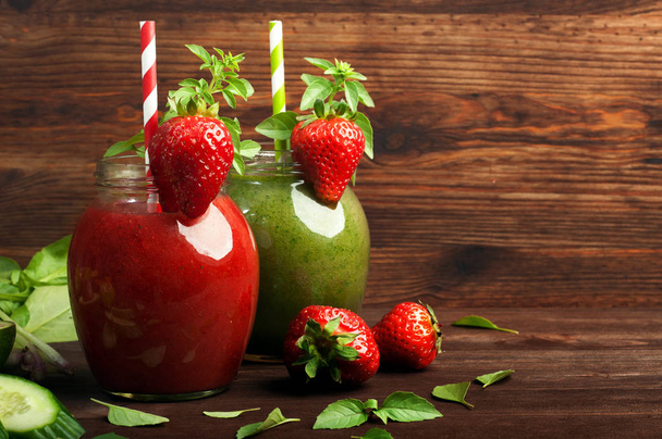 Trendy hipster drink on a brown wooden background. Red Berry smoothie with strawberries and green smoothie of apples, avocados and spinach. Space for text. Healthy and tasty diet drinks for detox - Fotoğraf, Görsel