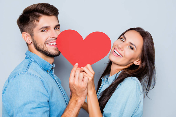 Portrait of two cheerful lovers holding red paper heart  - Photo, image