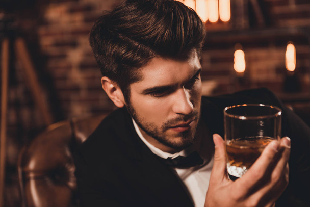 Portrait of rich handsome man holding glass of cognac and relaxi - Zdjęcie, obraz