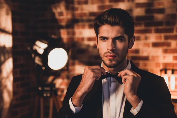 Portait of confident handsome man corecting his bow tie and wear - Foto, Bild