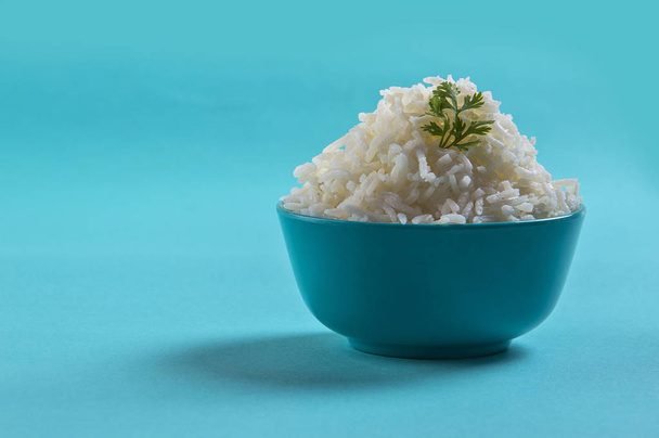 Cooked plain white basmati rice with corriander in a blue bowl on blue background - Fotoğraf, Görsel