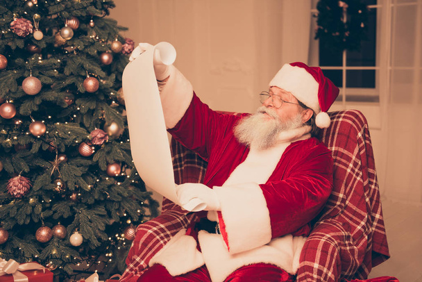 Aged happy Santa Claus reading wishes of xmas presents - Φωτογραφία, εικόνα